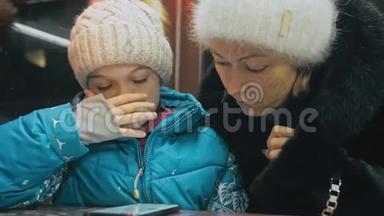 漂亮的白种人母女使用智能手机坐在咖啡馆里。 高级幼儿表演和<strong>讲解</strong>